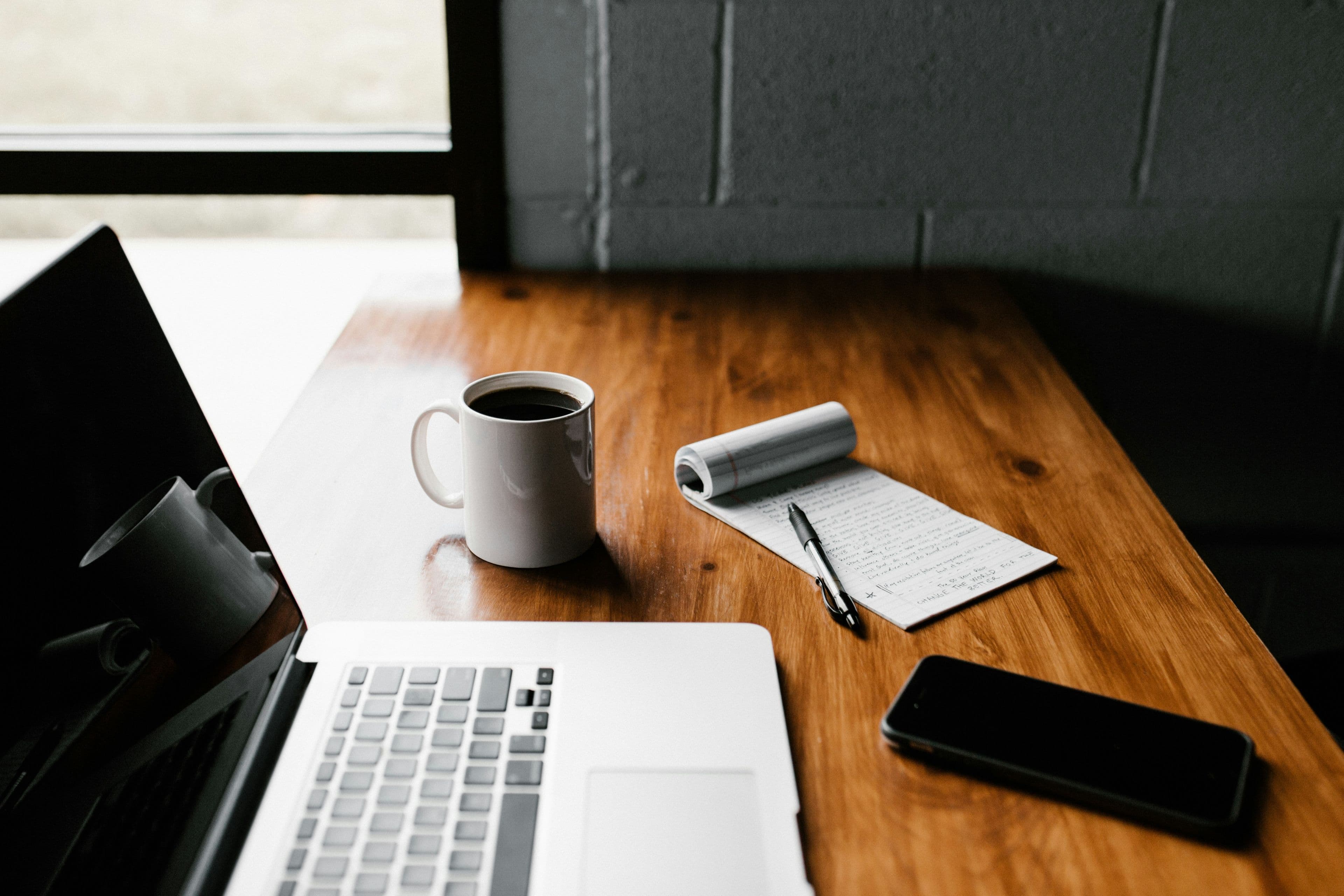 An open laptop on a desk with a cup of coffee nearby