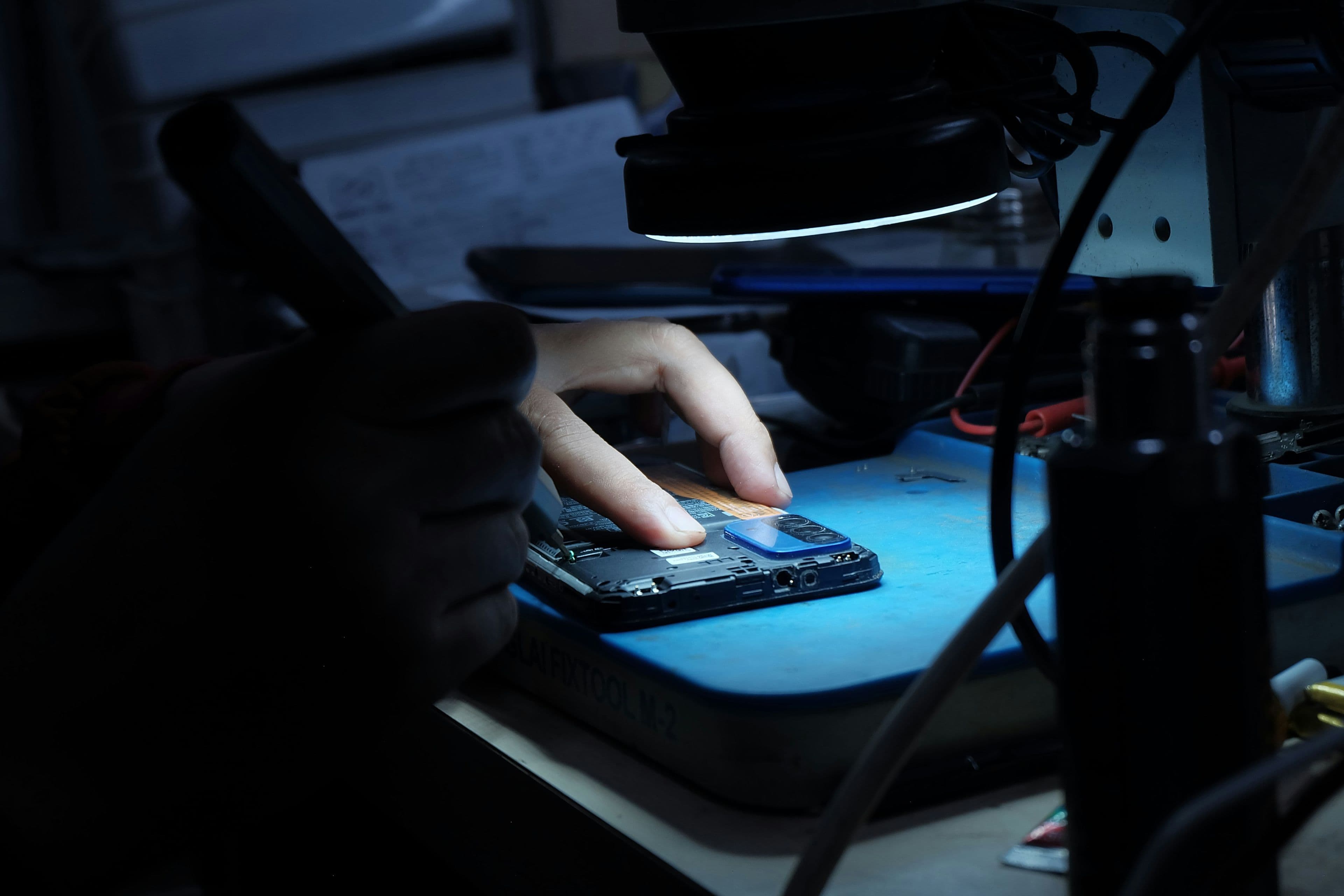 A cluttered, well-used electronics workbench with tools and an opened gadget